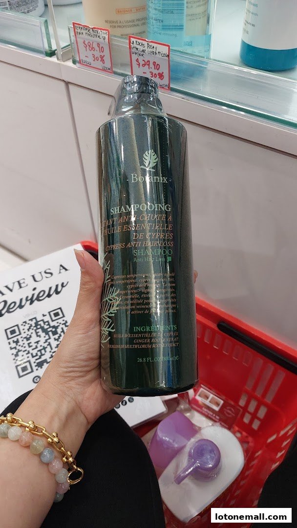 A person holds a large bottle of Botanix Cypress Anti Hair Loss Shampoo in a shopping basket.