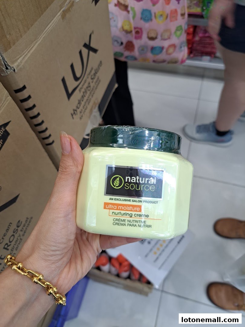A hand holds a jar of Natural Source ultra moisture nurturing creme.
