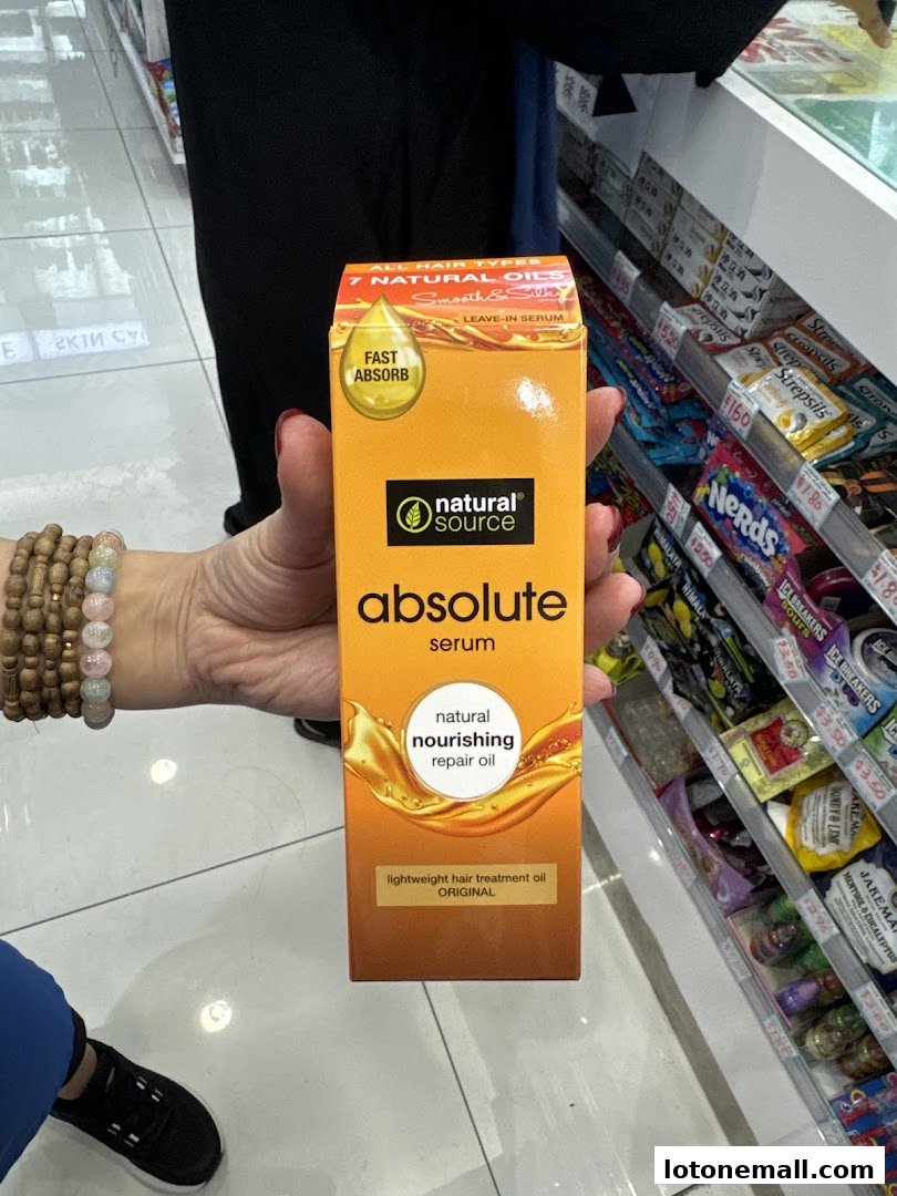 A person holds a box of Natural Source Absolute Serum hair treatment oil in a store.