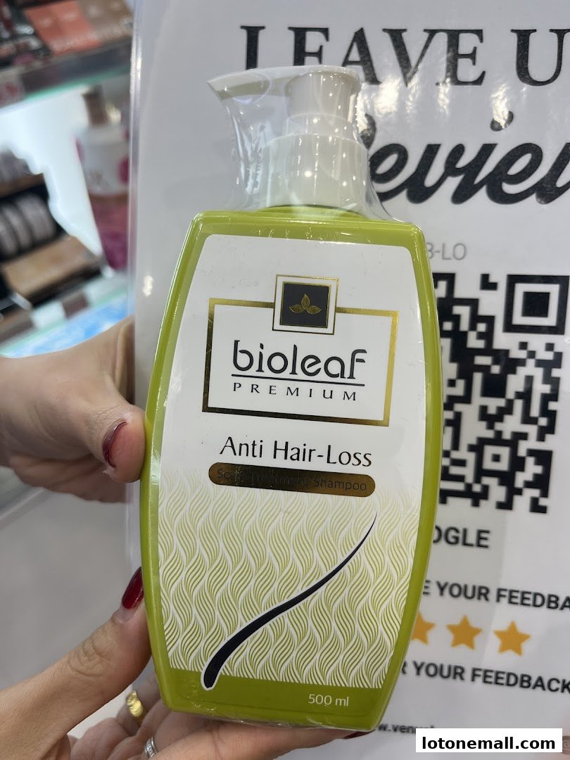 A hand holds a bottle of Bioleaf Premium Anti Hair-Loss Shampoo.