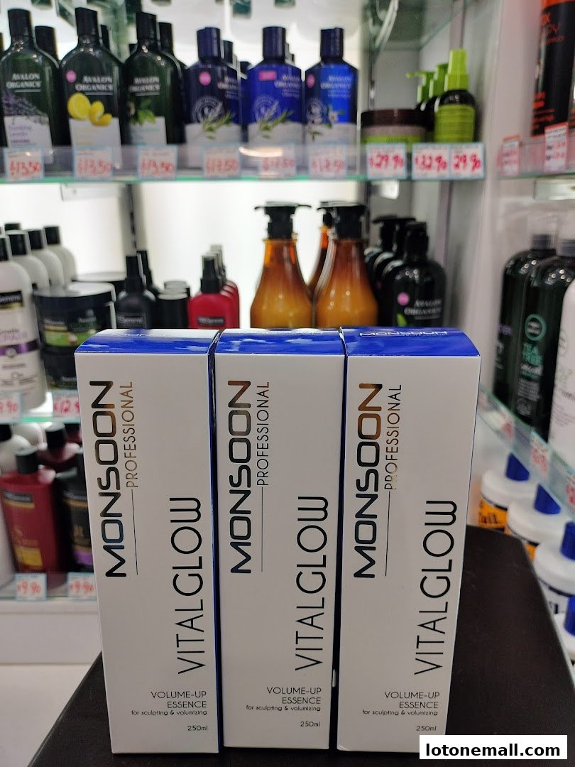 Three boxes of Monsoon Professional Vital Glow Volume-Up Essence are displayed in front of shelves stocked with beauty products.