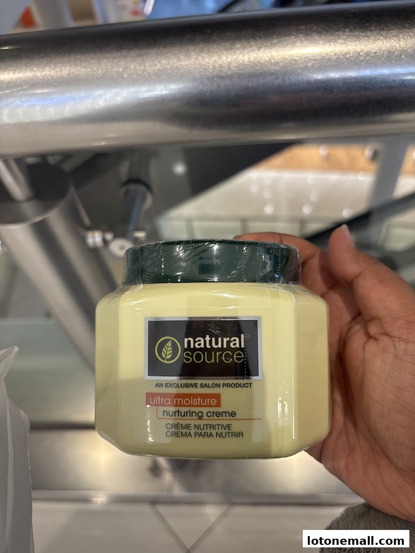 A hand holds a jar of Natural Source Ultra Moisture Nurturing Creme.