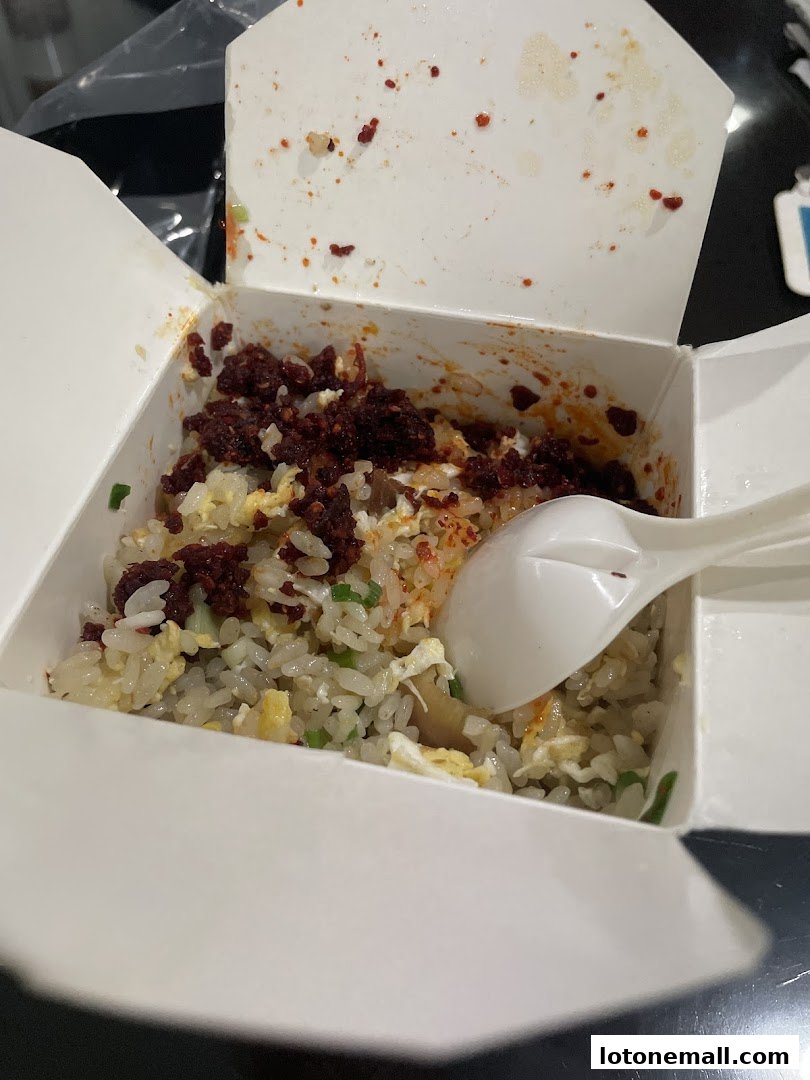 A close-up of a takeaway box filled with fried rice and a spoon.