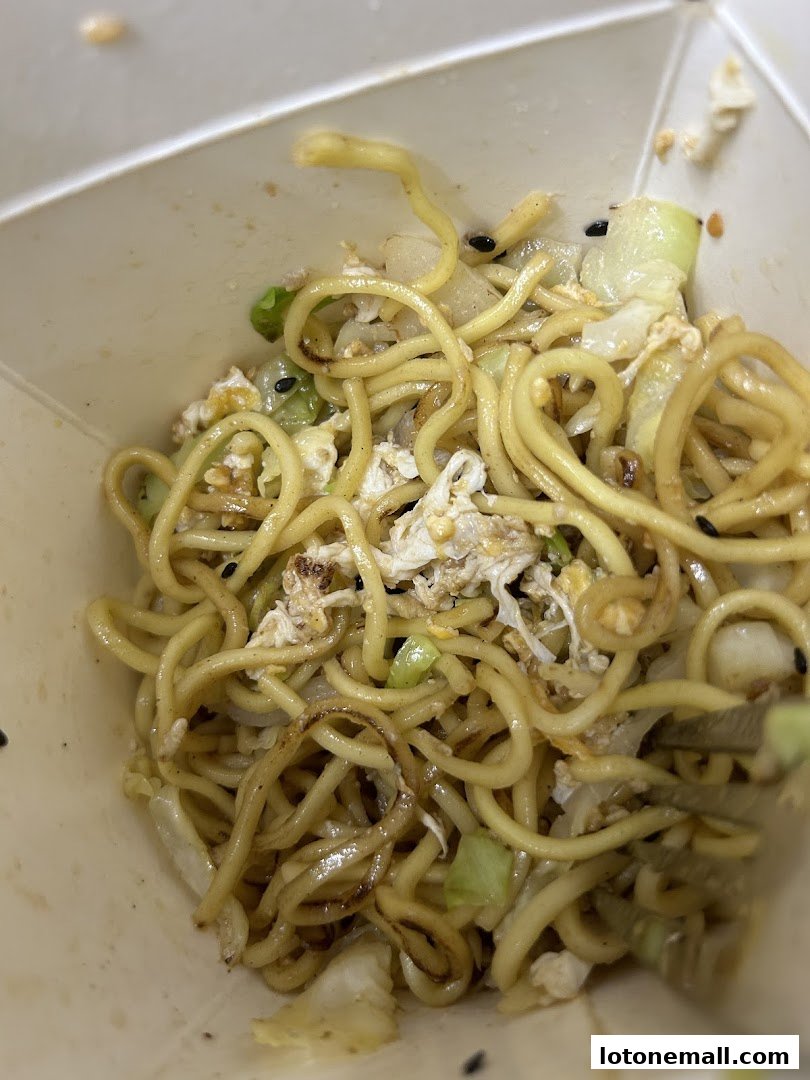 A close-up shot of a takeaway box filled with delicious stir-fried noodles and vegetables.
