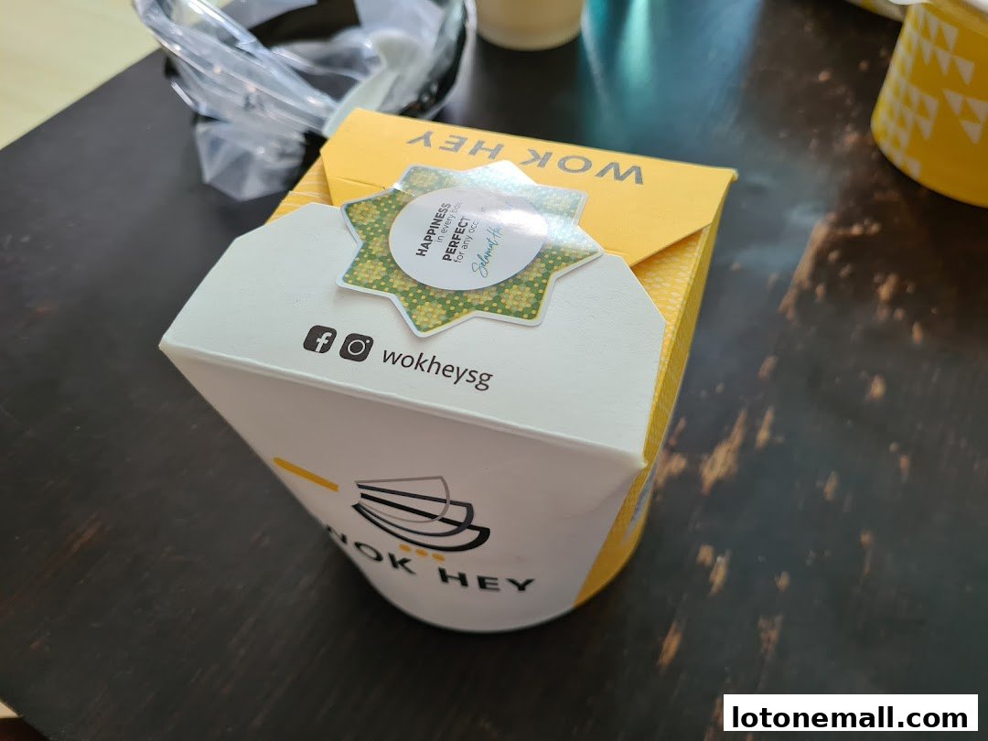 A Wok Hey takeaway box with branding and social media icons.
