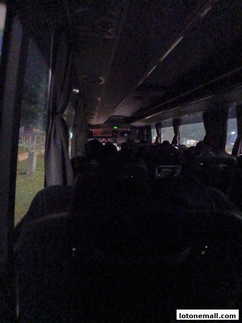 Interior view of a bus with dark seats and curtains, seen from the perspective of a passenger.