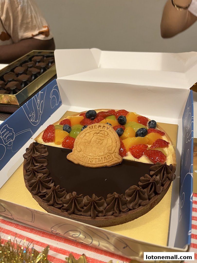 A festive fruit tart with chocolate frosting and a 'Merry Christmas' cookie.