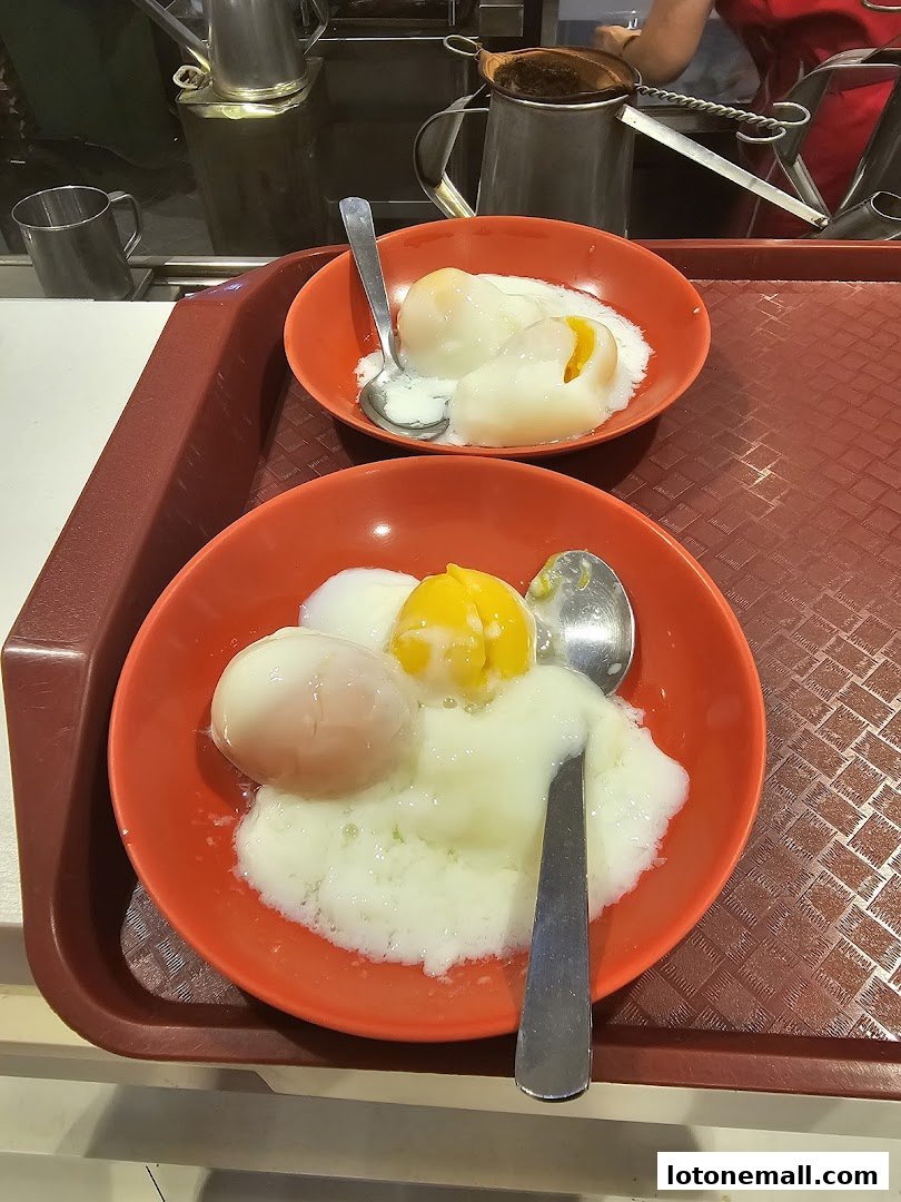 Two bowls of soft-boiled eggs with a side of kaya and butter toast.
