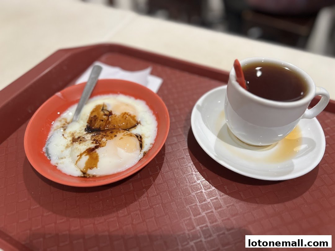 A close-up of soft-boiled eggs with soy sauce and a cup of tea on a tray.