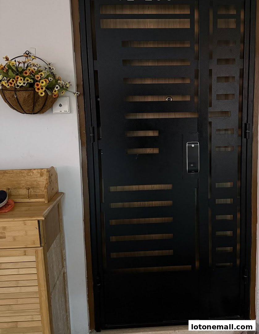 A modern black metal gate with a digital lock, next to a wooden cabinet and a hanging flower basket.