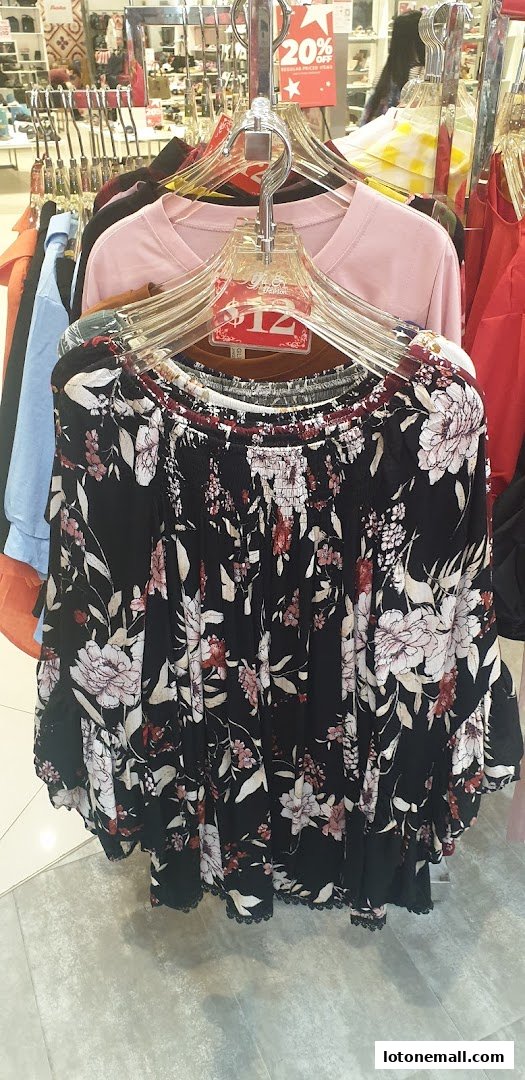 A floral off-the-shoulder top is displayed on a hanger with a price tag.