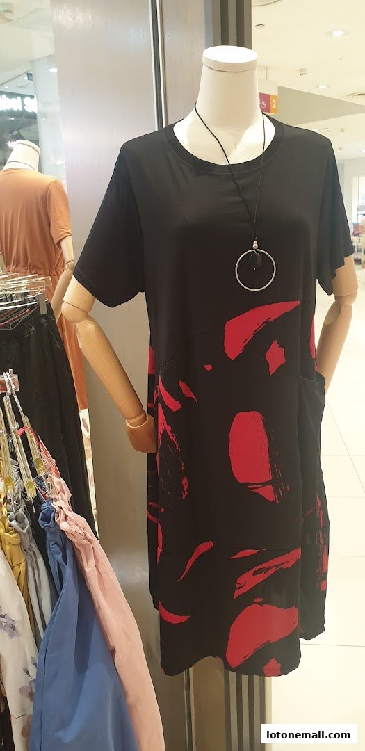 A mannequin displays a black dress with red abstract print and a silver pendant necklace.