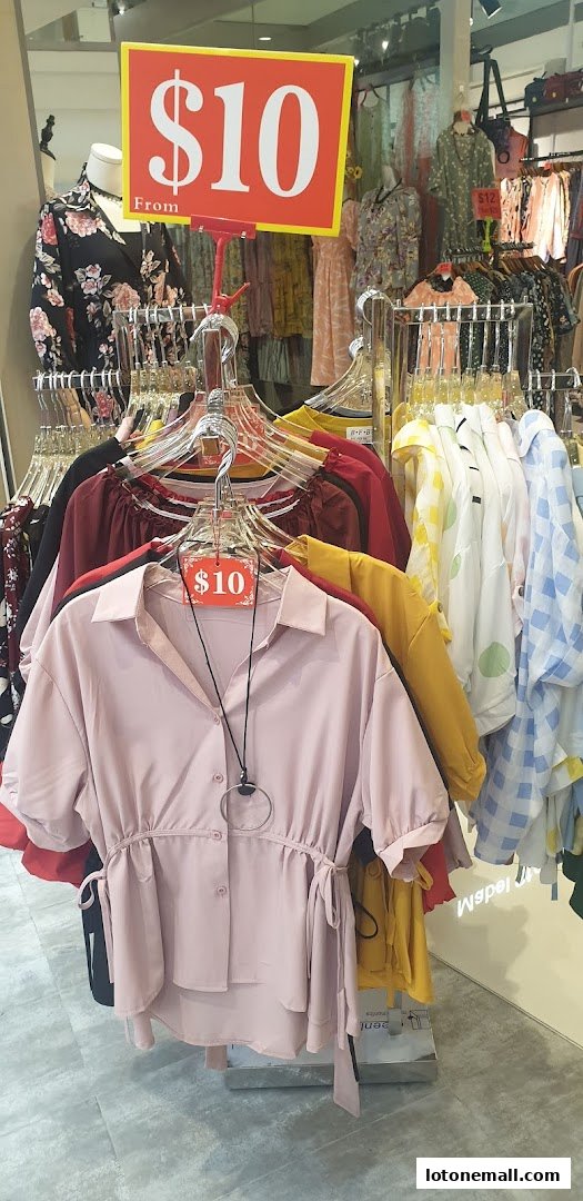 A display of women's clothing on hangers with a prominent '$10' sale sign.