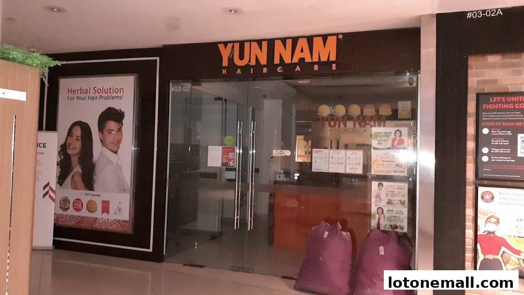 The entrance of Yun Nam Hair Care, featuring their branding and promotional posters.