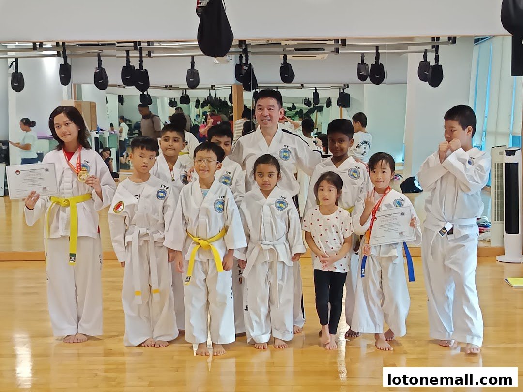 A group of children in Taekwondo uniforms with a coach, some holding certificates and medals.