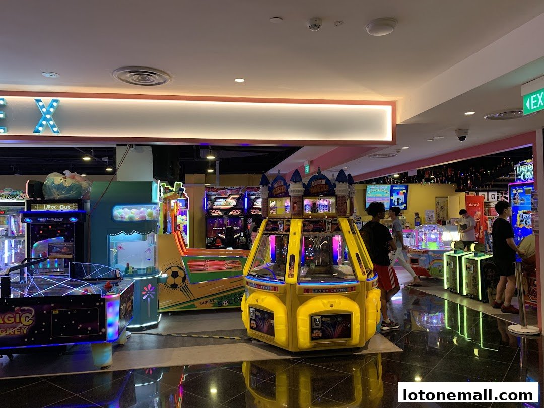 Interior view of an arcade with various game machines and people playing.