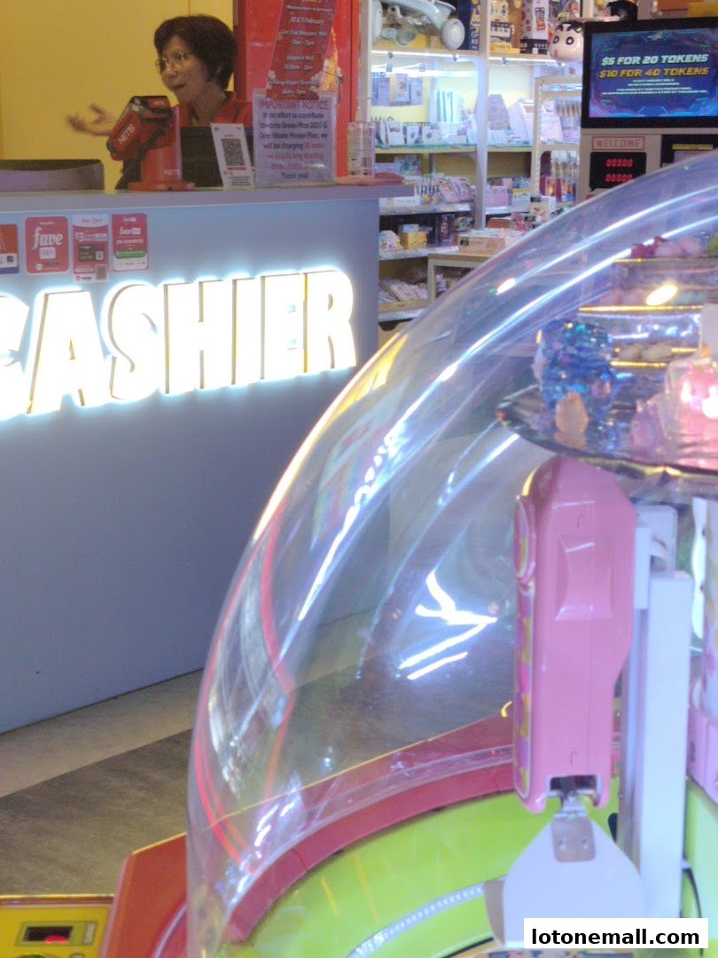 A cashier counter with glowing text and an arcade claw machine in the foreground.
