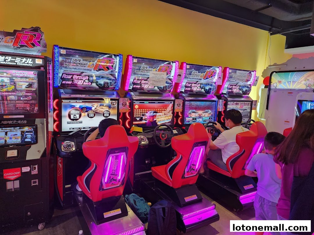 People playing racing arcade games at Zone X, with bright lights and colorful machines.