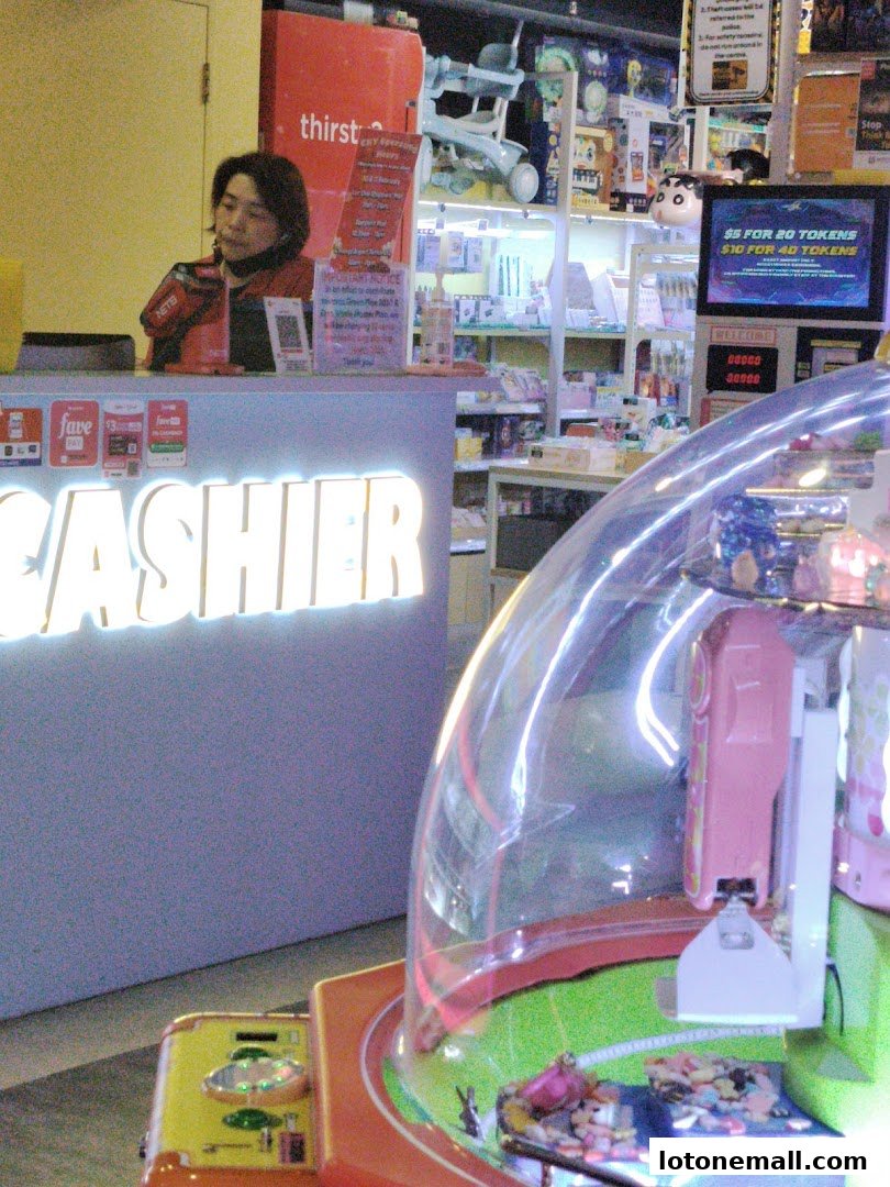 A cashier counter with an arcade game in the foreground and shelves of merchandise in the background.